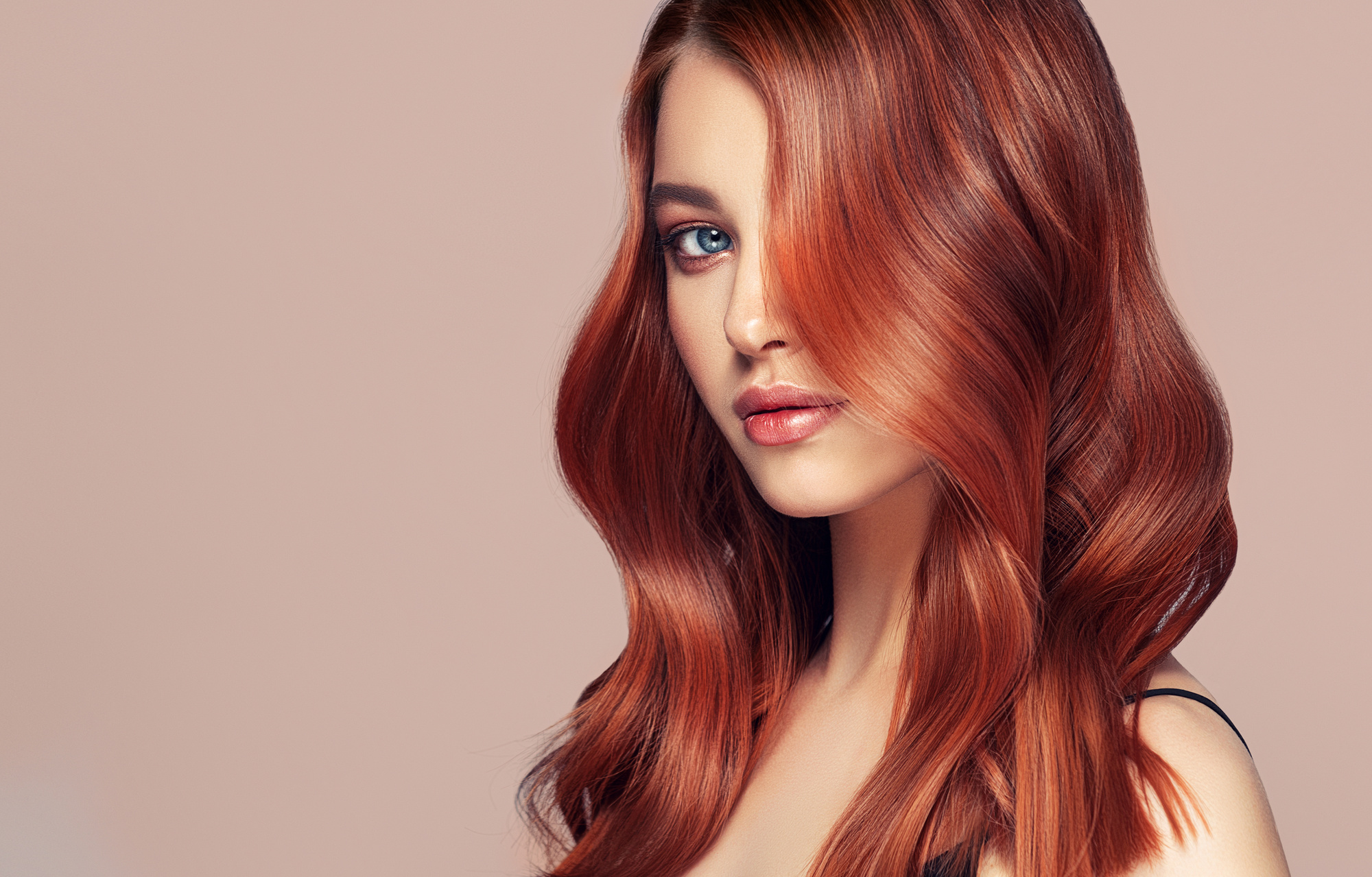 Young, red haired beautiful model with long, curly, well groomed hair. Excellent hair waves. Hairdressing art and hair care.